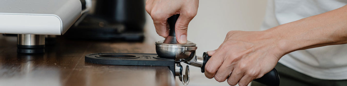 barista making coffee with portafilter and tamper